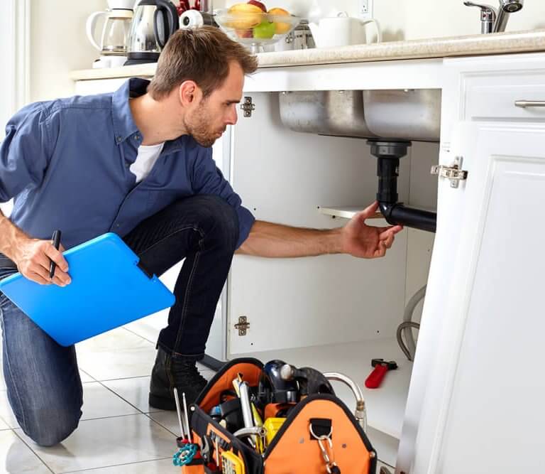 Man looking at plumbing under sink